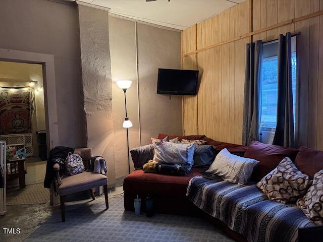 carpeted living room featuring wood walls