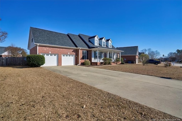 cape cod-style house featuring a garage, a front lawn, and covered porch