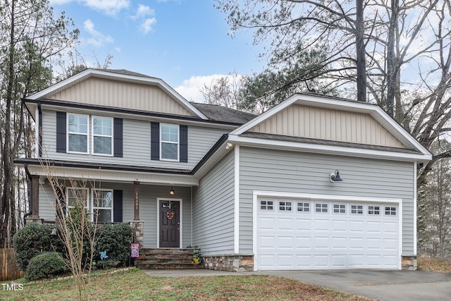 view of front of house featuring a porch, stone siding, driveway, and a garage