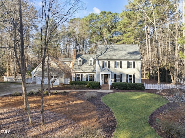 view of front of property featuring fence, a chimney, driveway, a garage, and a front yard