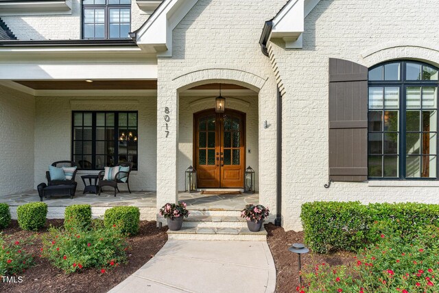 doorway to property featuring covered porch and brick siding
