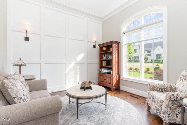 living room featuring plenty of natural light, ornamental molding, wood finished floors, and visible vents