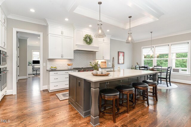 kitchen featuring crown molding, a kitchen breakfast bar, dark wood finished floors, and white cabinetry