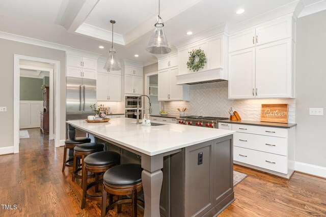kitchen featuring recessed lighting, a sink, a tray ceiling, and ornamental molding