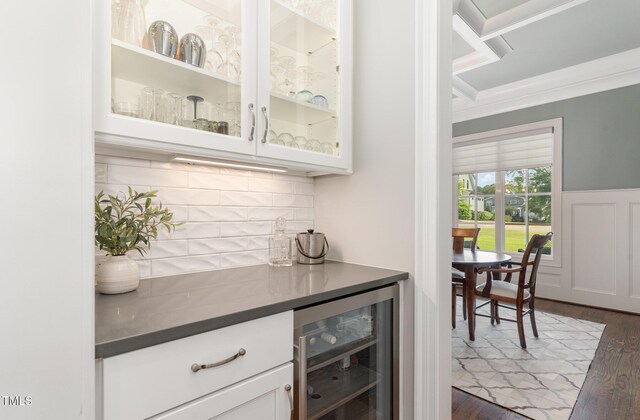 bar with backsplash, ornamental molding, dark wood-type flooring, and wine cooler