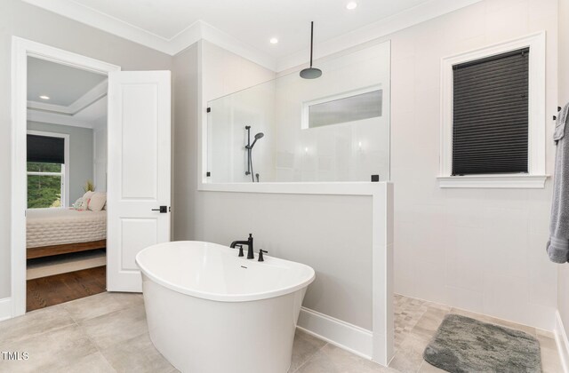 ensuite bathroom featuring crown molding, walk in shower, ensuite bath, and a freestanding bath