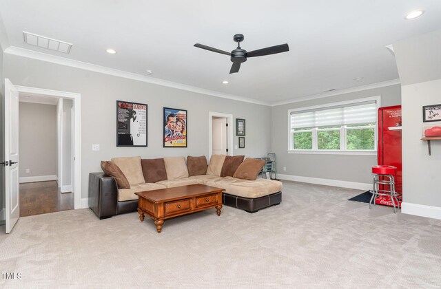 living area featuring ceiling fan, light colored carpet, baseboards, visible vents, and ornamental molding