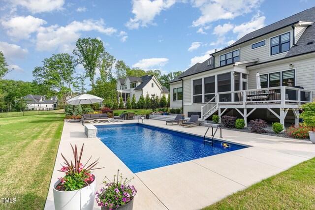 view of pool with fence, a patio, a sunroom, a fenced in pool, and a lawn