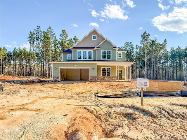 craftsman-style house with stone siding, a garage, board and batten siding, driveway, and covered porch