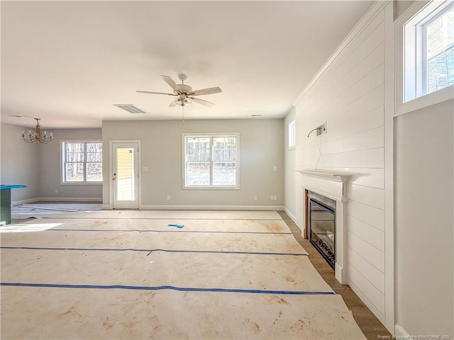 unfurnished living room with a large fireplace, ceiling fan with notable chandelier, baseboards, and visible vents