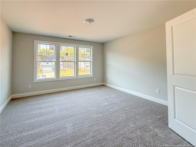 carpeted empty room featuring baseboards