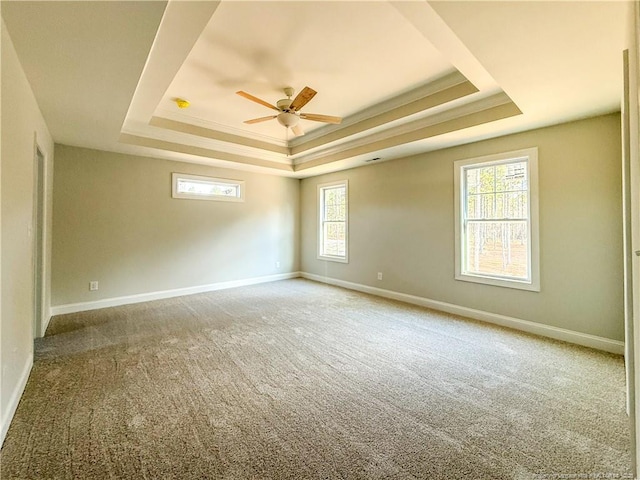 carpeted spare room with baseboards, a tray ceiling, a ceiling fan, and ornamental molding