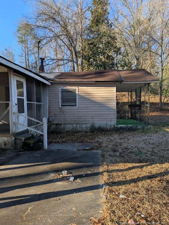 view of home's exterior featuring a sunroom and a carport