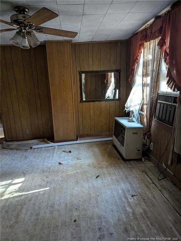 empty room with ceiling fan, wooden walls, and light hardwood / wood-style flooring