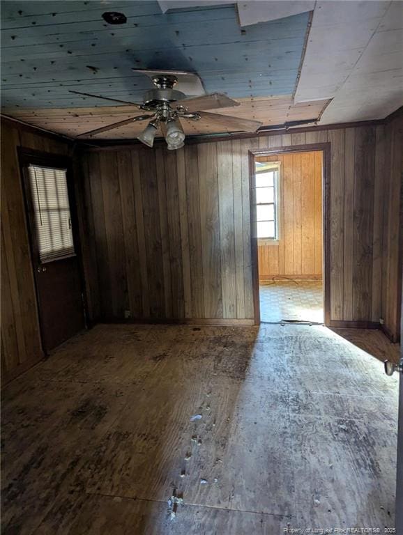 empty room featuring wood-type flooring, ceiling fan, and wood walls