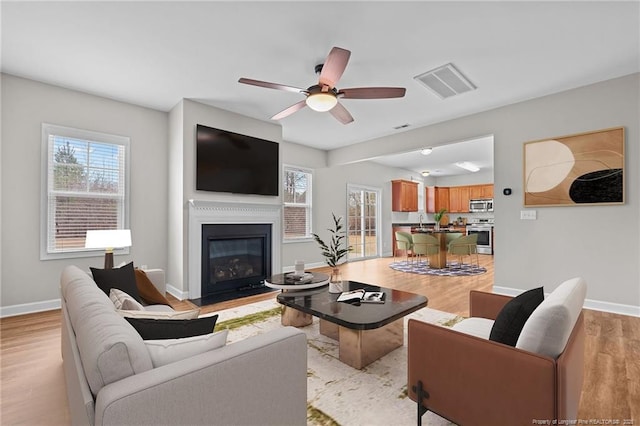 living area with visible vents, baseboards, and light wood-style flooring