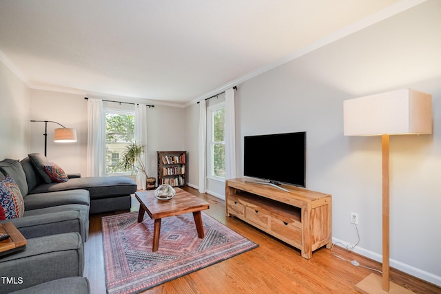 living area with crown molding, baseboards, and light wood finished floors