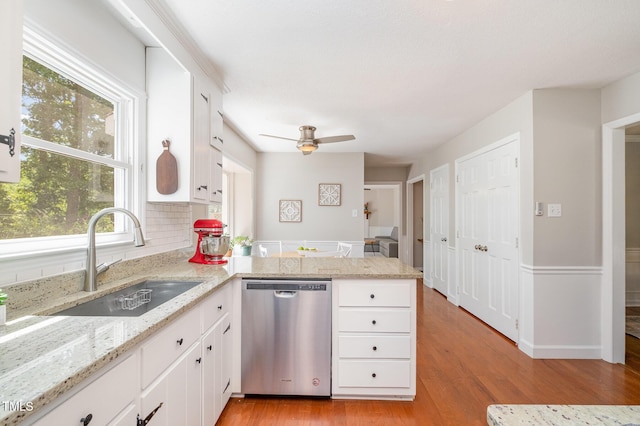 kitchen with white cabinets, a sink, dishwasher, a peninsula, and light wood-type flooring