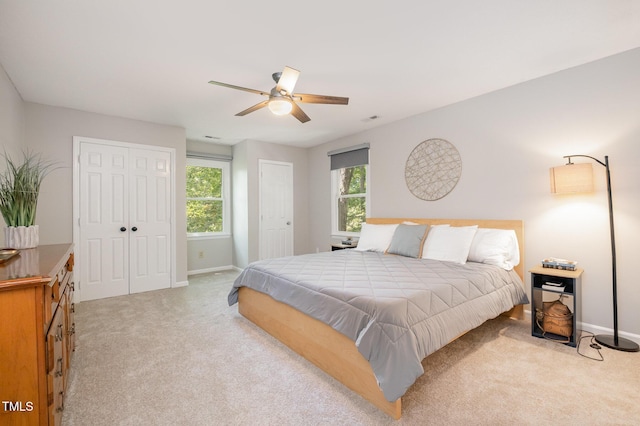 bedroom featuring multiple closets, baseboards, and light carpet