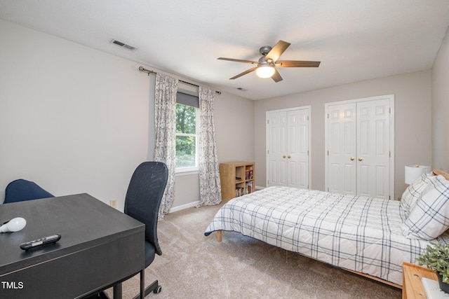 bedroom with visible vents, two closets, light carpet, baseboards, and a ceiling fan