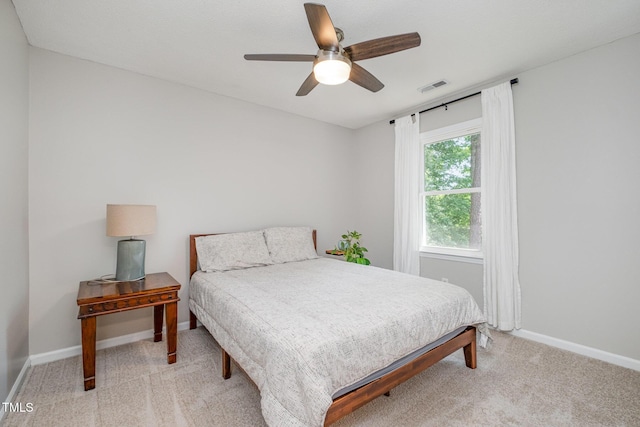 bedroom featuring visible vents, a ceiling fan, baseboards, and light colored carpet