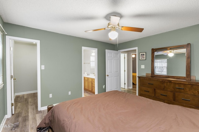 bedroom featuring a spacious closet, connected bathroom, a textured ceiling, and light wood-type flooring