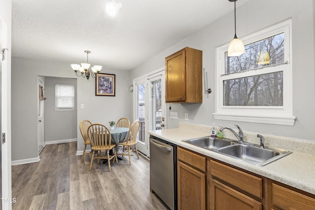 kitchen featuring dishwasher, sink, pendant lighting, and light hardwood / wood-style flooring