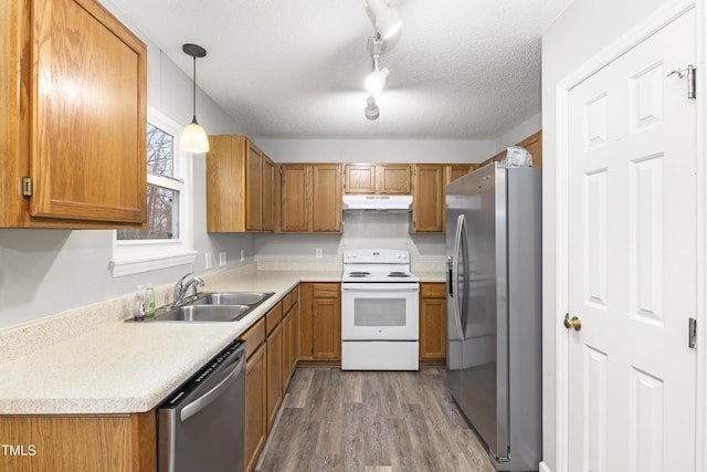 kitchen with sink, a textured ceiling, appliances with stainless steel finishes, pendant lighting, and light hardwood / wood-style floors