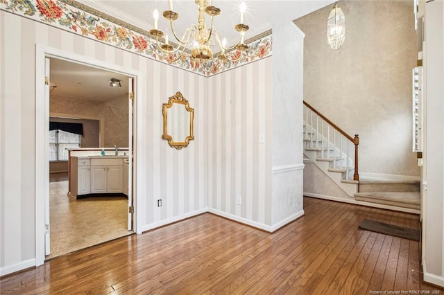 empty room with wood-type flooring, sink, and an inviting chandelier