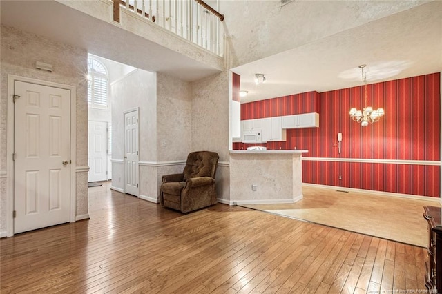 interior space featuring an inviting chandelier, wood-type flooring, and a high ceiling