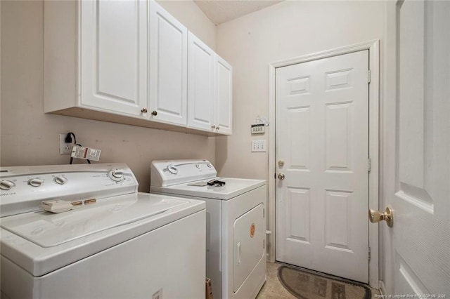 clothes washing area with cabinets and washer and clothes dryer