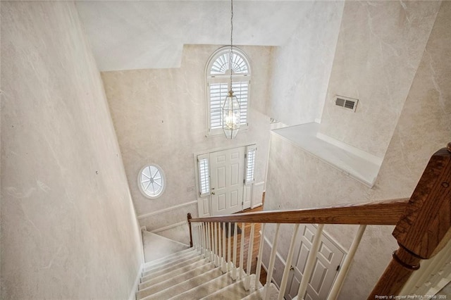 staircase featuring a notable chandelier and a high ceiling