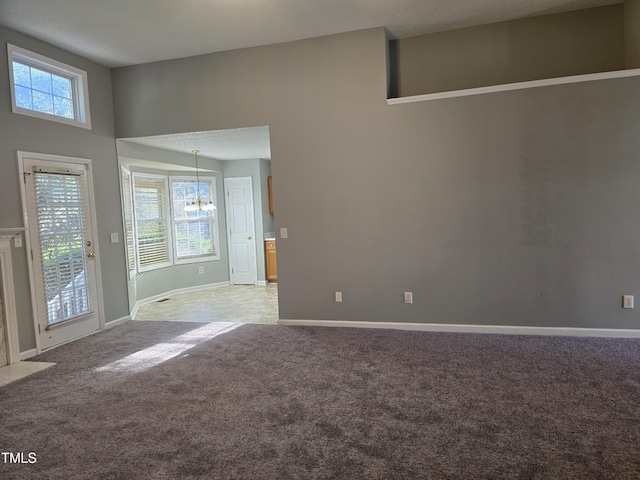 spare room featuring baseboards, carpet flooring, a wealth of natural light, and a notable chandelier