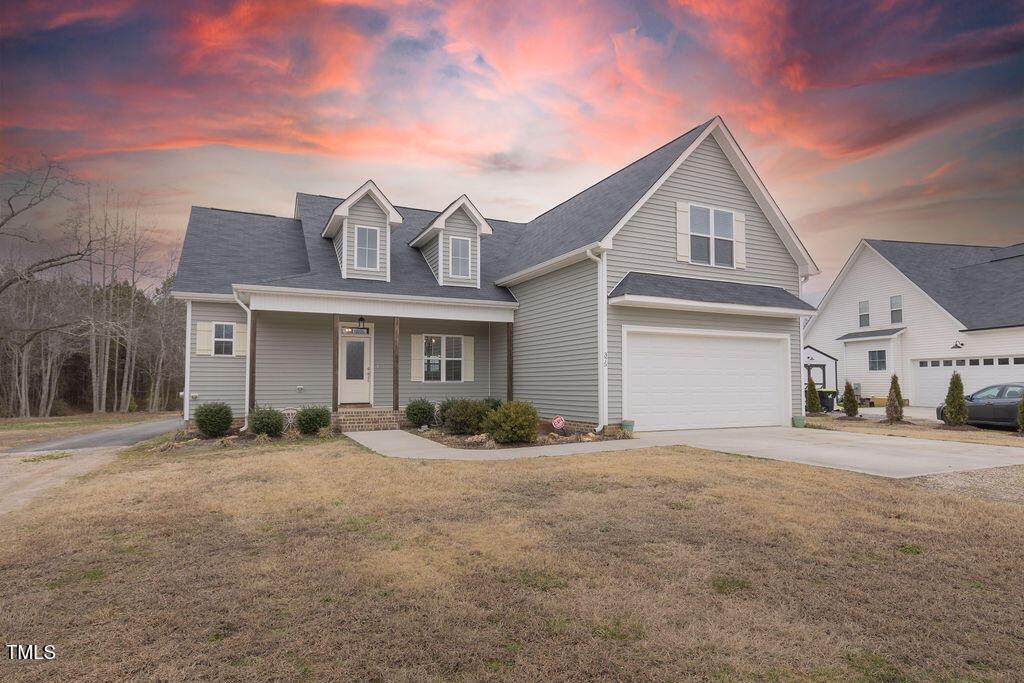 view of front of home featuring a porch, a garage, and a yard