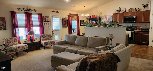 living room with lofted ceiling, a notable chandelier, and light carpet