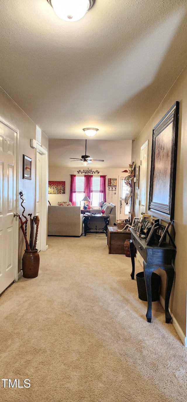 living room featuring ceiling fan, carpet, and a textured ceiling