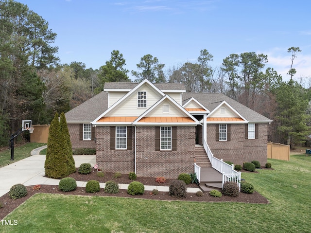 view of front facade featuring a front lawn, a standing seam roof, roof with shingles, metal roof, and brick siding