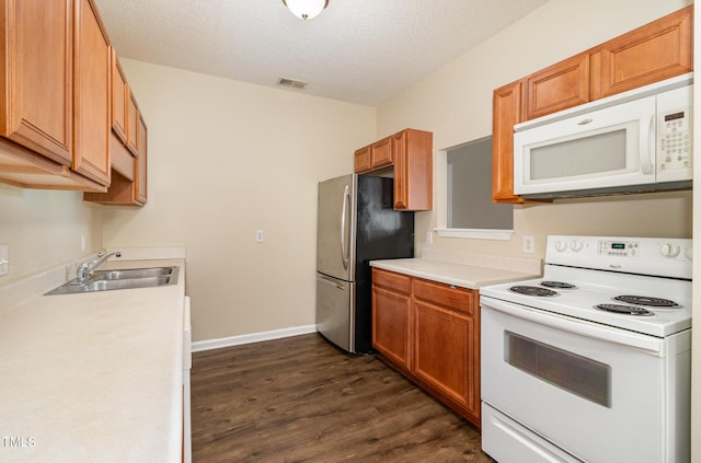 kitchen featuring sink, dark wood-type flooring, a textured ceiling, and white appliances