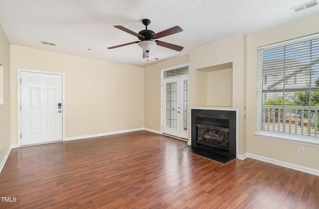 unfurnished living room featuring ceiling fan, dark wood-type flooring, and a textured ceiling