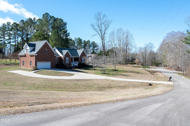 exterior space with a garage, driveway, brick siding, and a front yard