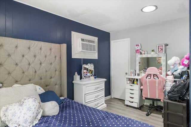 bedroom with a wall unit AC and light hardwood / wood-style flooring