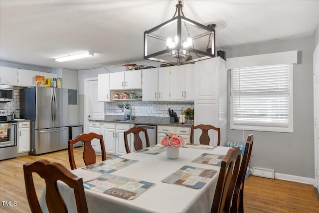 dining space featuring an inviting chandelier, sink, and light hardwood / wood-style floors