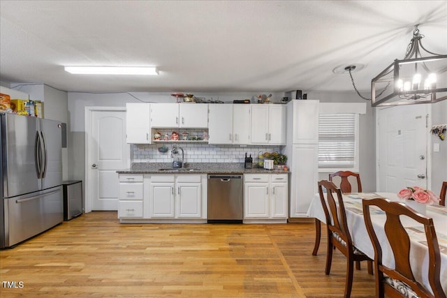 kitchen featuring sink, light wood-type flooring, pendant lighting, stainless steel appliances, and white cabinets