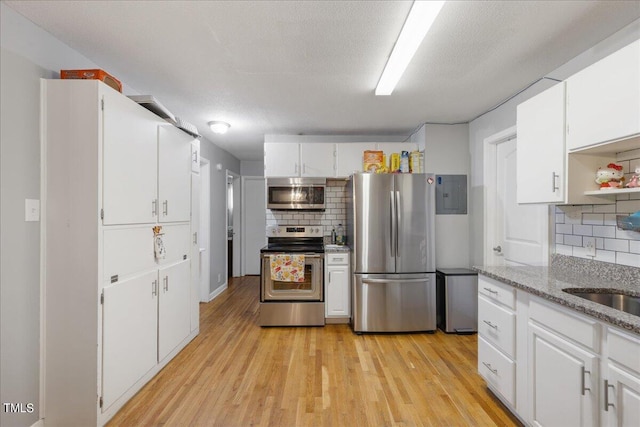 kitchen featuring white cabinetry, light hardwood / wood-style flooring, stainless steel appliances, and tasteful backsplash