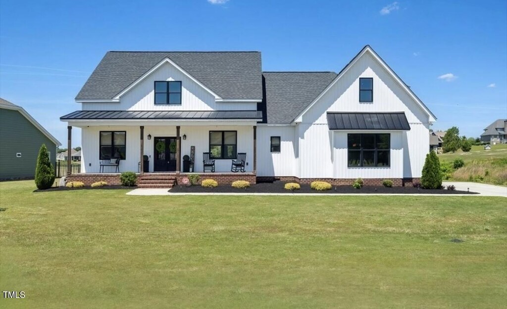 121 Masters Way, Goldsboro, NC 27530 - view of front facade featuring roof with shingles, a front lawn, a standing seam roof, covered porch, and metal roof