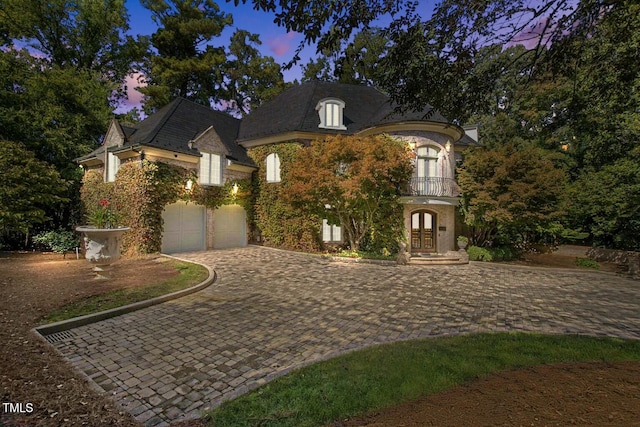 french country style house with french doors, a garage, and a balcony