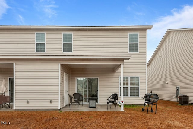 back of house featuring cooling unit, a lawn, and a patio