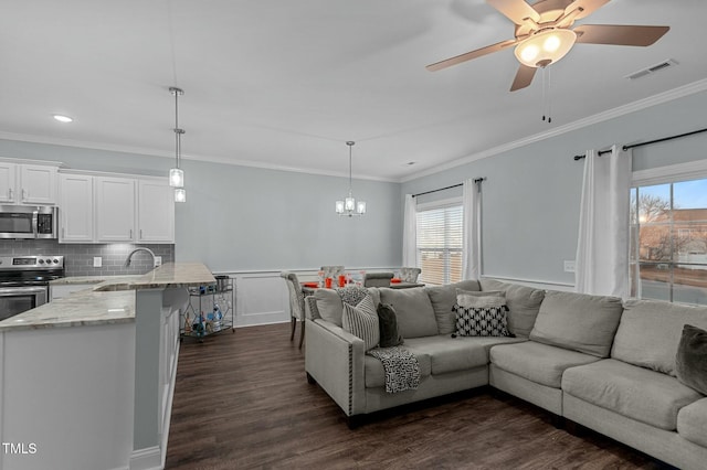 living room with dark hardwood / wood-style flooring, sink, crown molding, and ceiling fan with notable chandelier