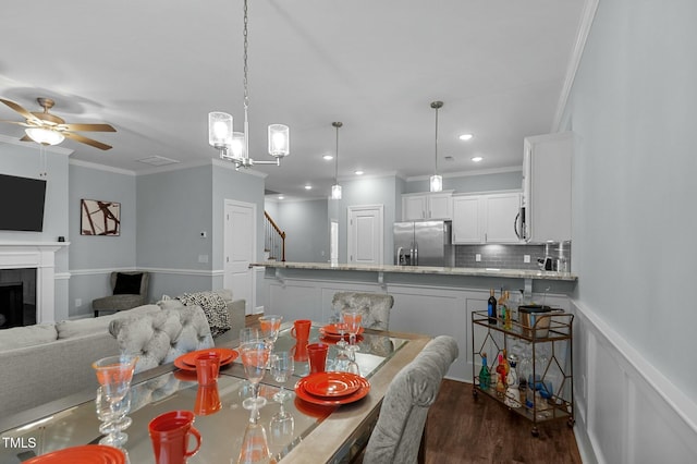 dining area with ornamental molding, dark wood-type flooring, and ceiling fan