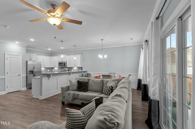 living room with crown molding, ceiling fan with notable chandelier, and hardwood / wood-style flooring